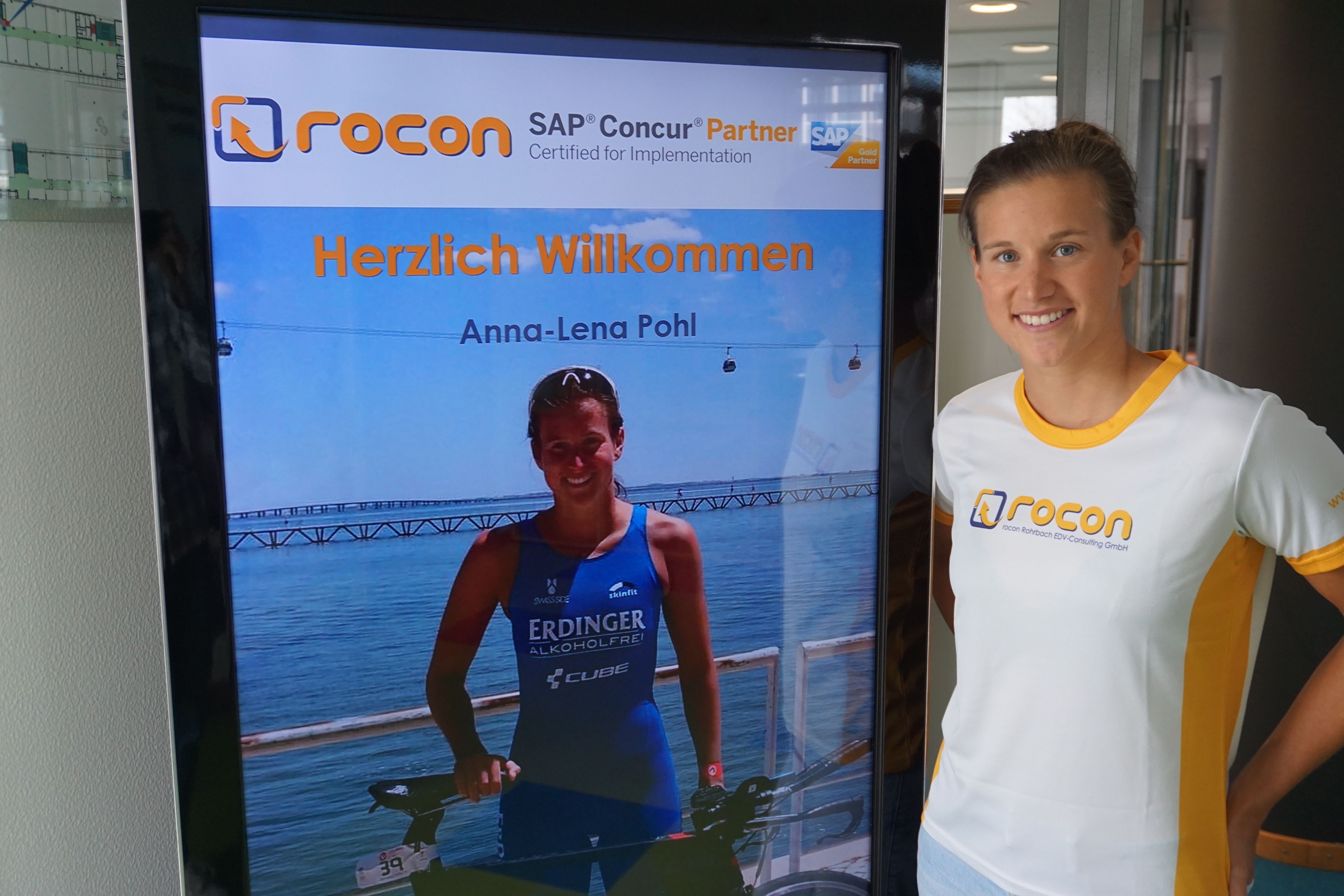 Die Triathletin aus Mainz Anna Lena Pohl vor Ihrem Plakat auf dem die Partnerschaft mir Rocon dargestellt wird.