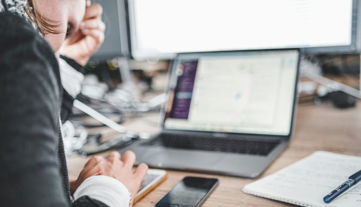 Mitarbeiterin vor Laptop und mobilen Endgeräten