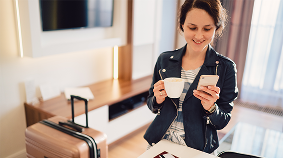 Digitale Strategie Mobile First mit einer Frau und einem Handy in der Hand während sie Kaffee trinkt