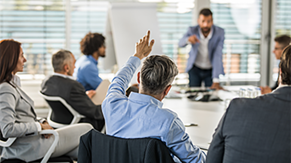 Discuss Business Processes in einem Meeting mit mehreren Personen während sich ein Mann meldet