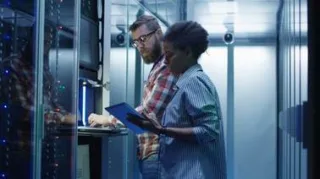 Datensicherheit Managed Hosting in einem Serverraum während ein Mann und eine Frau zusammenstehen