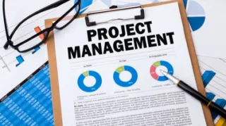 Ein Klemmbrett auf dem Projektmanagement drauf steht