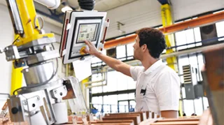Digitalisierung Big Data bei der ein Mann vor einer Maschine steht und daten über das Tablet eingibt