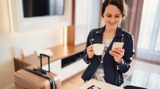 Digitale Strategie Mobile First mit einer Frau und einem Handy in der Hand während sie Kaffee trinkt