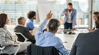 Discuss Business Processes in einem Meeting mit mehreren Personen während sich ein Mann meldet