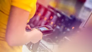 Eine weibliche Hand hält in einem Lager ein mobiles Scangerät in der Hand