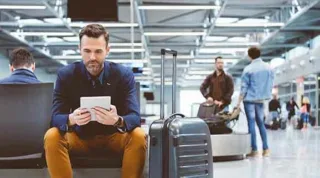 Ein Mann mit einem Tablet in der Hand sitzt am Check In