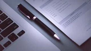 Ein schwarzer Kugelschreiber liegt zwischen einem Laptop und einer Abrechnung