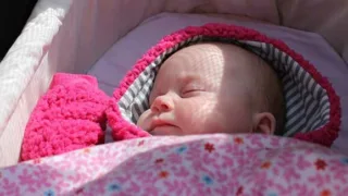 Schlafendes Baby in pinkem Wolljäckchen, schlafend im Kinderwagen