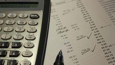 Ein Taschenrechner liegt auf einer Bilanz und daneben ein Kugelschreiber