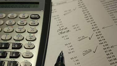 Ein dargestellter Taschenrechner liegt auf einem Stück Papier beim Accounting Jahresabschluss